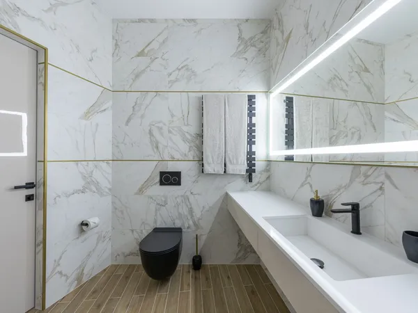 Marble-tiled en-suite with a wall-hung toilet, vanity basin and heated towel rail