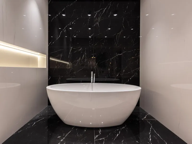 Modern bathroom with a white freestanding bath against a black marble feature wall